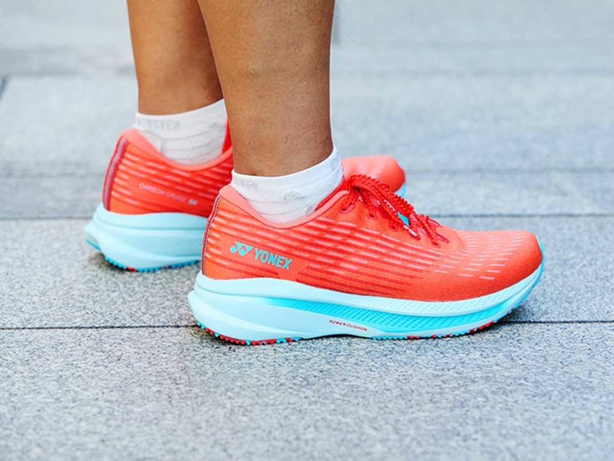 Yonex Sunrise Sports India stake illustrated by an exact Yonex Carbon Cruise XR shoe being worn outdoors.